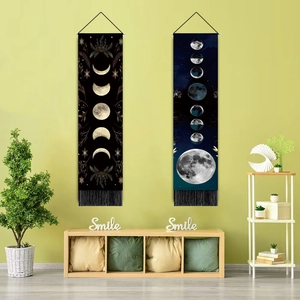 Détail de tapisseries phases de lune avec motifs floraux et pompons sur un mur vert clair