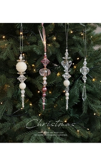 Close-up of pearl and acrylic bead ornaments hanging on a Christmas tree with warm lights