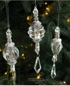 Close-up of three clear acrylic icicle ornaments hanging on a festive Christmas tree