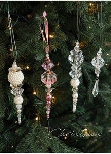 Detailed view of clear acrylic and pearl Christmas ornaments hanging on a festive tree