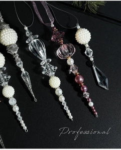 Detail of four icicle ornaments with transparent crystal and white pearls on black background