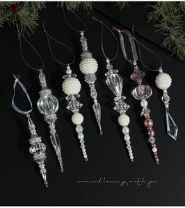 Close-up of acrylic and silver metal Christmas ornaments with pearls on pine background