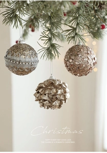 Detailed view of champagne gold glitter Christmas balls hanging on pine tree branches