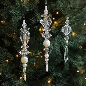 Three acrylic crystal Christmas ornaments with pearls hanging on a lit Christmas tree