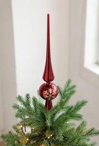 Detail van rode metalen kerstboompiek met gouden sneeuwvlokken op een versierde kerstboom