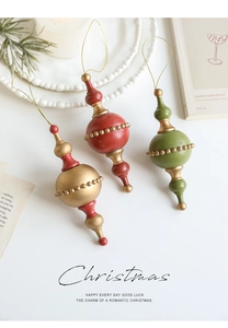 Close-up of vintage Christmas tree ornaments with gold beads on a white surface