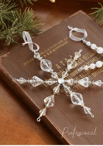 Pendentif flocon de neige en acrylique transparent sur livre ancien et branche de pin