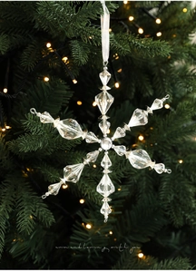 Détail d'un pendentif flocon de neige en acrylique suspendu sur un sapin de Noël illuminé