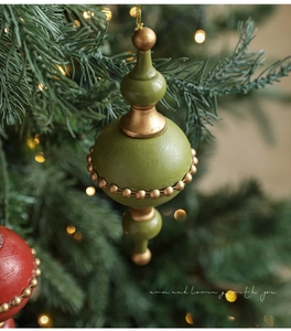 Detail of vintage olive green and gold Christmas ornament hanging on a pine tree