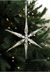 Détail de décoration flocon transparent sur sapin de Noël avec lumières chaudes bokeh
