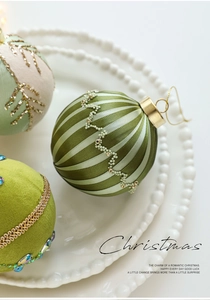 Détail de boules de Noël en velours avec strass et perles dans un plateau blanc chic