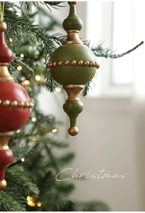 Close-up of red and olive green wooden Christmas tree ornaments with gold bead accents