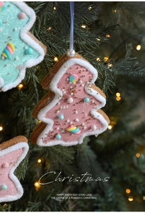 Detailed view of pink and blue gingerbread tree ornaments with beads on a lit Christmas tree