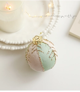 Détail d'une boule de Noël en tissu vert menthe et beige avec motifs pailletés dorés