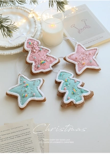 Close-up of glittery pink and blue Christmas star and tree ornaments with gingerbread texture