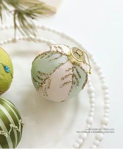 Vue macro d'une boule de Noël en tissu beige de 8cm avec motifs dorés brillants