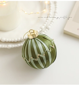 Détail d'une boule de Noël à rayures vertes avec perles dorées et lumières de fête