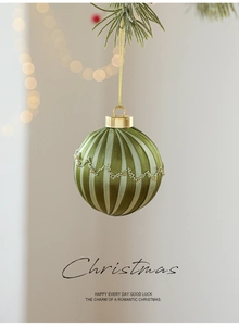 Gros plan d'une boule de Noël en satin vert avec dentelle perlée sur une branche de sapin