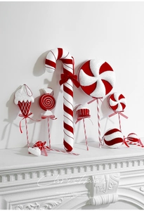 Détail d'ornements de Noël en velours rouge et blanc en forme de bonbons sur une cheminée