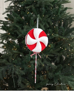 Détail d'une sucette de Noël rouge et blanche pailletée sur un sapin de Noël