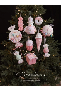Detail of pink macaron and cupcake Christmas ornaments on a lighted tree branch