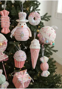 Close-up of pink macaron and candy Christmas ornaments hanging on a lit tree