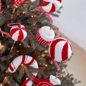 Décorations de Noël en velours rouge et blanc sur un sapin avec lumières