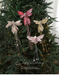 Detail of four colorful feather bird ornaments with sequins on a lit Christmas tree