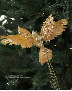 Close-up of golden bird ornament with sequins and pearls on green Christmas tree branch