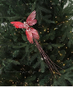 Detail of red feathered bird ornament with white pearls on a green Christmas tree branch
