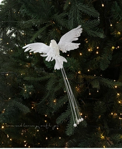 Close-up of white decorative bird with sequins and pearls hanging on a Christmas tree