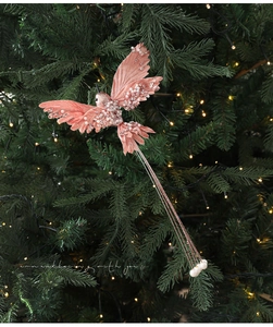Detailed view of pink artificial bird ornament with sequins and pearls on Christmas tree