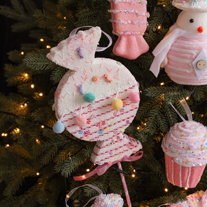 Pink candy Christmas tree ornaments with macarons and cupcakes on a lit holiday tree
