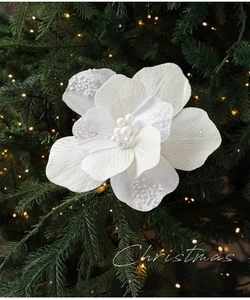 Detail van witte kerstbloem met glitter en parels op een groene kerstboom