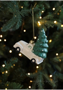 Detail of a white vintage ceramic truck ornament with a snowy tree on a Christmas tree