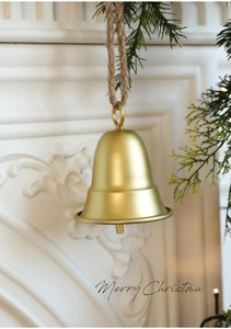 Campana di Natale in metallo dorato opaco con corda appesa vicino al camino