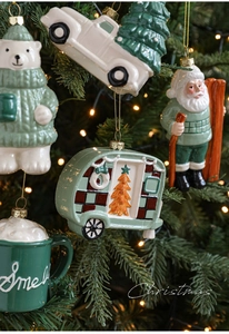 Close-up of ceramic Christmas ornaments featuring polar bear and Santa on tree branches