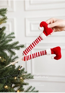 Détail de jambes d'elfe rayées rouge et blanc avec bottes en velours pour sapin de Noël