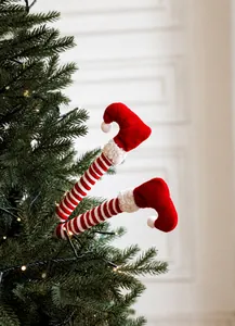 Detail van rood-wit gestreepte elfenpoten decoratie gestoken in een verlichte kerstboom