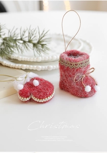 Detail of red plush Christmas boot ornaments with gold lace and white pom-poms on a tree