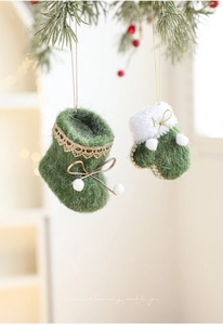 Detail of green felt Christmas glove and boot ornaments hanging on pine branches