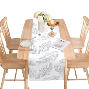 Elegant white table runner with grey palm leaf print on light wood dining table