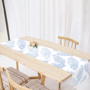 Linen table runner with blue tropical leaf prints on a white background for dining decor
