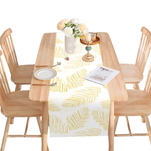 Camino de mesa blanco moderno con hojas de palma amarillas en mesa de madera clara