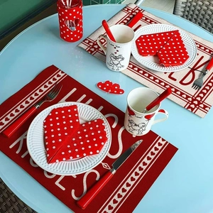 Détail d'un set de table rouge en lin avec lettrage KISSES et serviettes en cœur