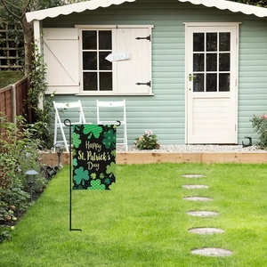 Outdoor garden view of St. Patrick's Day flag with clover patterns on a metal pole