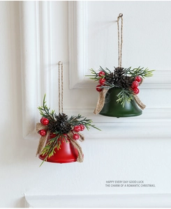 Detail of Christmas iron bells with pine cones, red berries and burlap bow on white wall