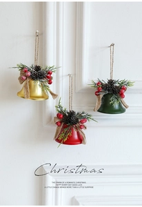Detail of Christmas iron bells with pine cones and red berries on a white wall