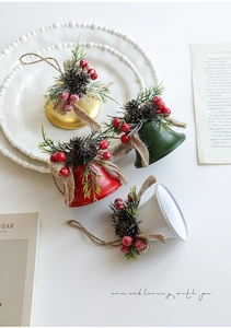 Detail of Christmas iron bells with pine needles, cones, berries and jute bows for decor