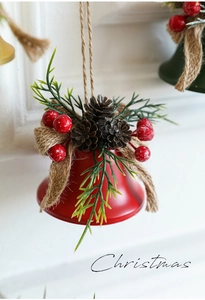 Macro view of a red metal Christmas bell with pine cones, red berries and green needles